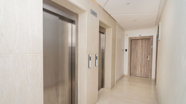 Area ascensori moderna con due cabine, una porta in legno e un cartello con la scritta 'ETAGE 6'.