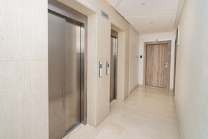 Un área moderna de ascensores con dos elevadores, una puerta de madera y un letrero que indica 'ETAGE 6'.