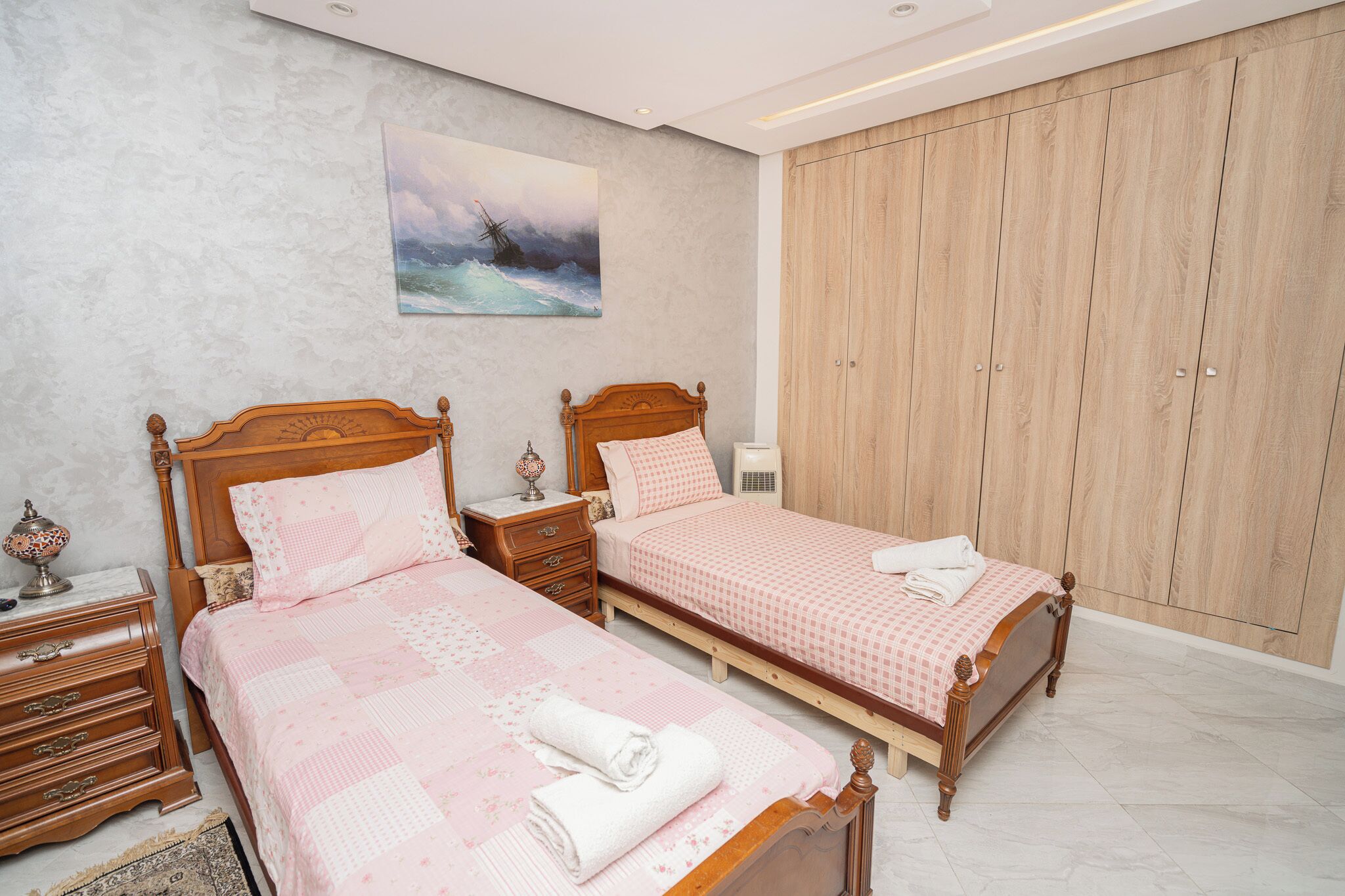Quarto com duas camas de madeira, um guarda-roupa espaçoso e um quadro na parede.