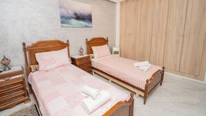 Una camera da letto con due letti in legno, un ampio guardaroba e un quadro appeso al muro.