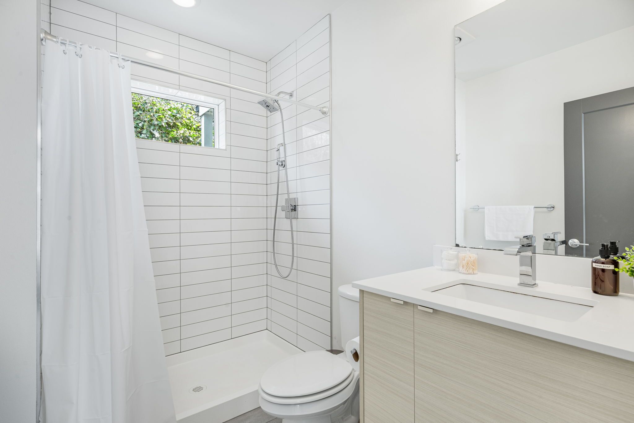 A modern bathroom with a shower, toilet, and sink.