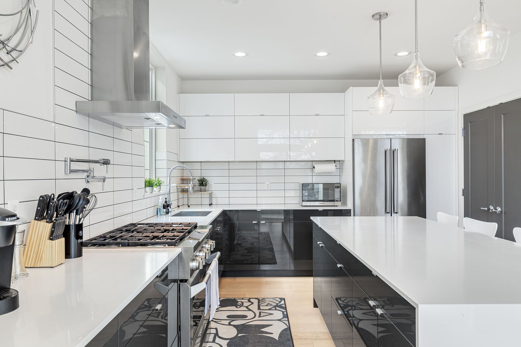 A modern kitchen with white cabinetry, stainless steel appliances, and pendant lighting.