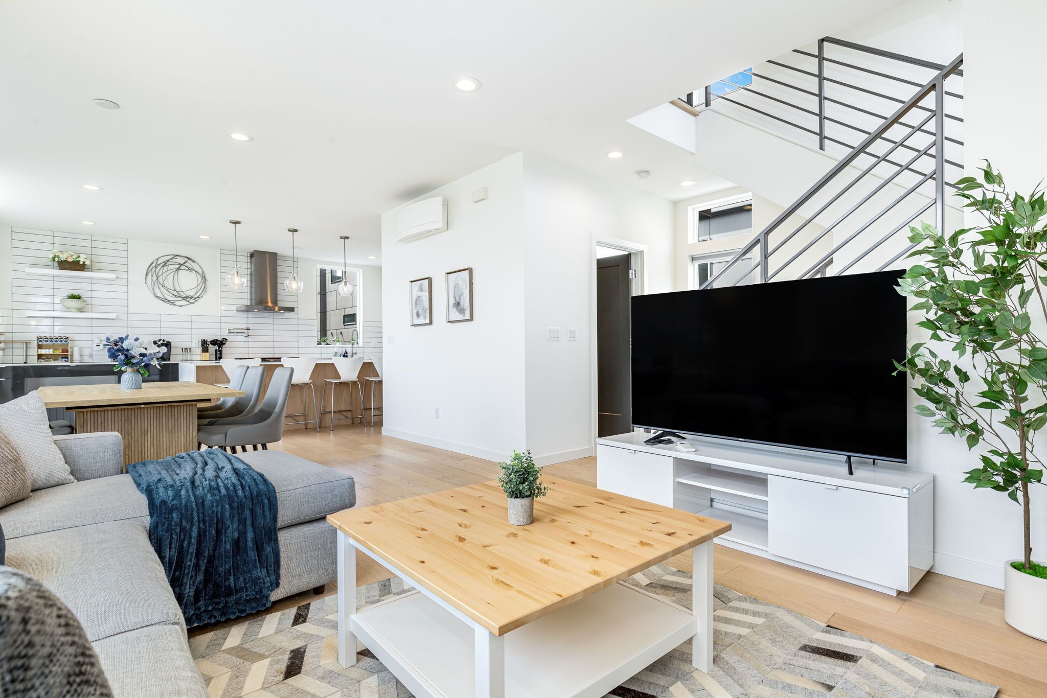 A modern living room with a sofa, coffee table, TV, and staircase.