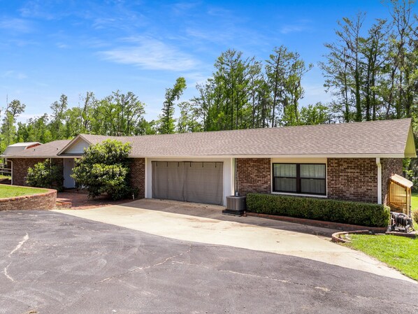 A two-story brick house with a garage, a covered porch, and a well-maintained lawn. - Merritt's Mill Pond Hideaway - 2.5 acres of waterfront paradise (Marianna)