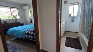 Une chambre à coucher avec un lit, une commode et une fenêtre agrémentée d’une plante.