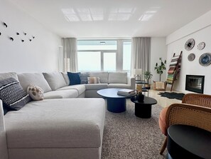 Moderni olohuone, jossa on kulmasohva, pyöreä sohvapöytä ja televisio.