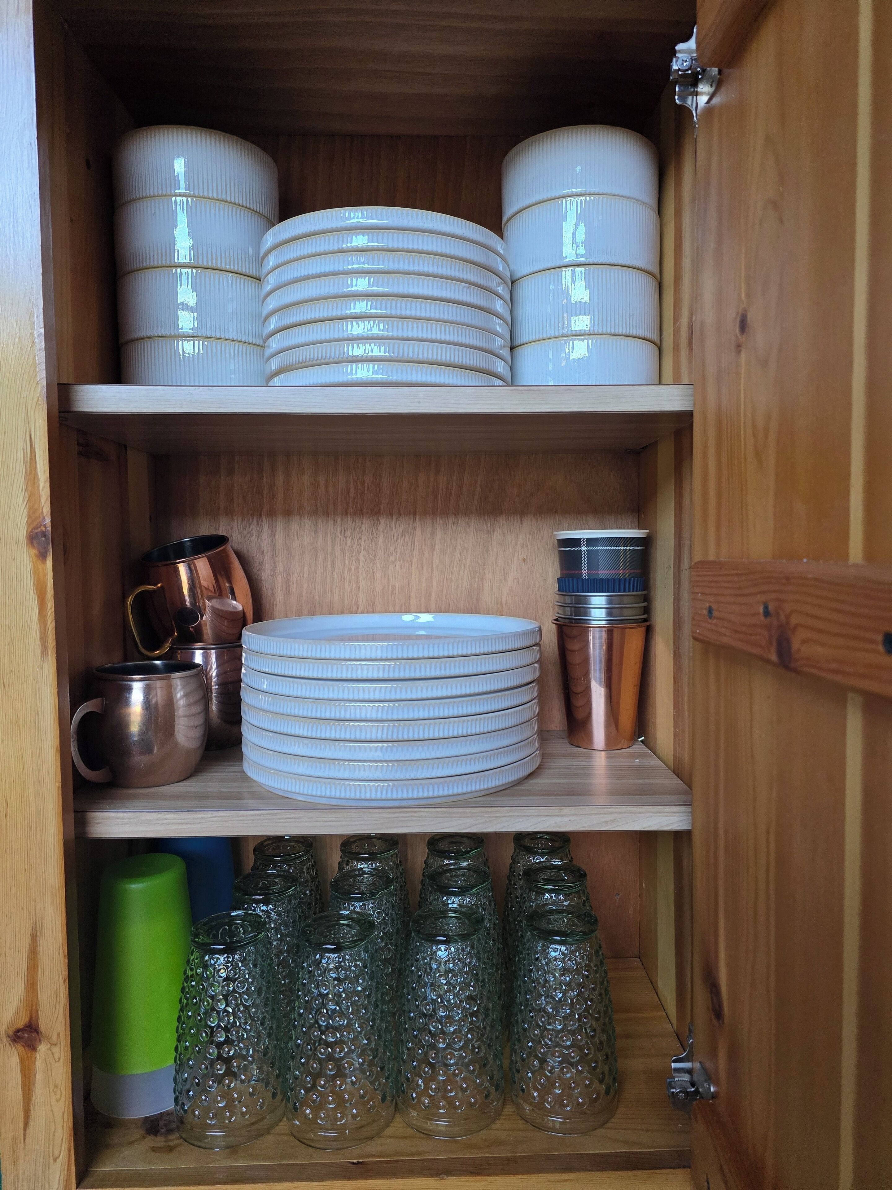 Un armario de madera con estantes que contienen varios utensilios de cocina.