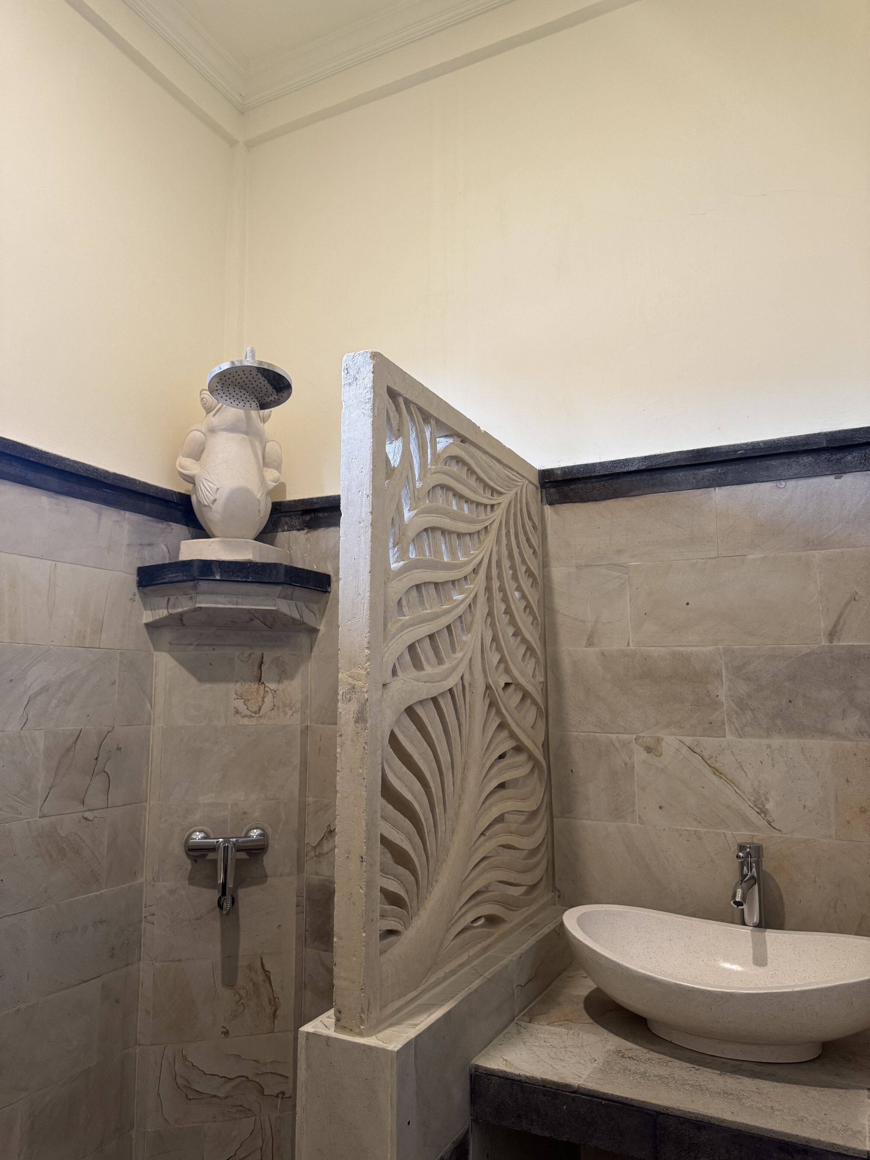 A bathroom with a sink, shower, and decorative panel.