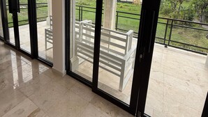 A spacious room with large sliding glass doors leading to a balcony with a white bench. - Murni's House (Buleleng)