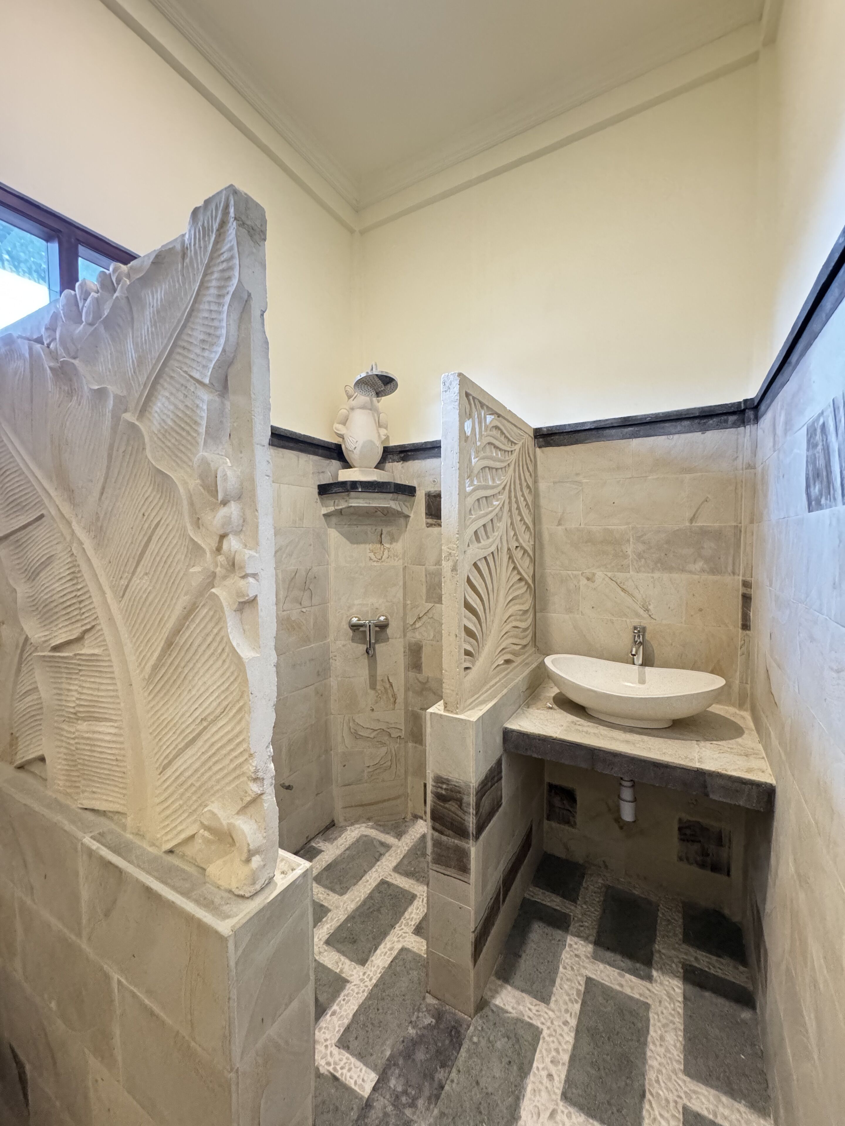 Ein Badezimmer mit einem SteinklopfZbecken, einer Dusche und einer dekorativen Steinwand.