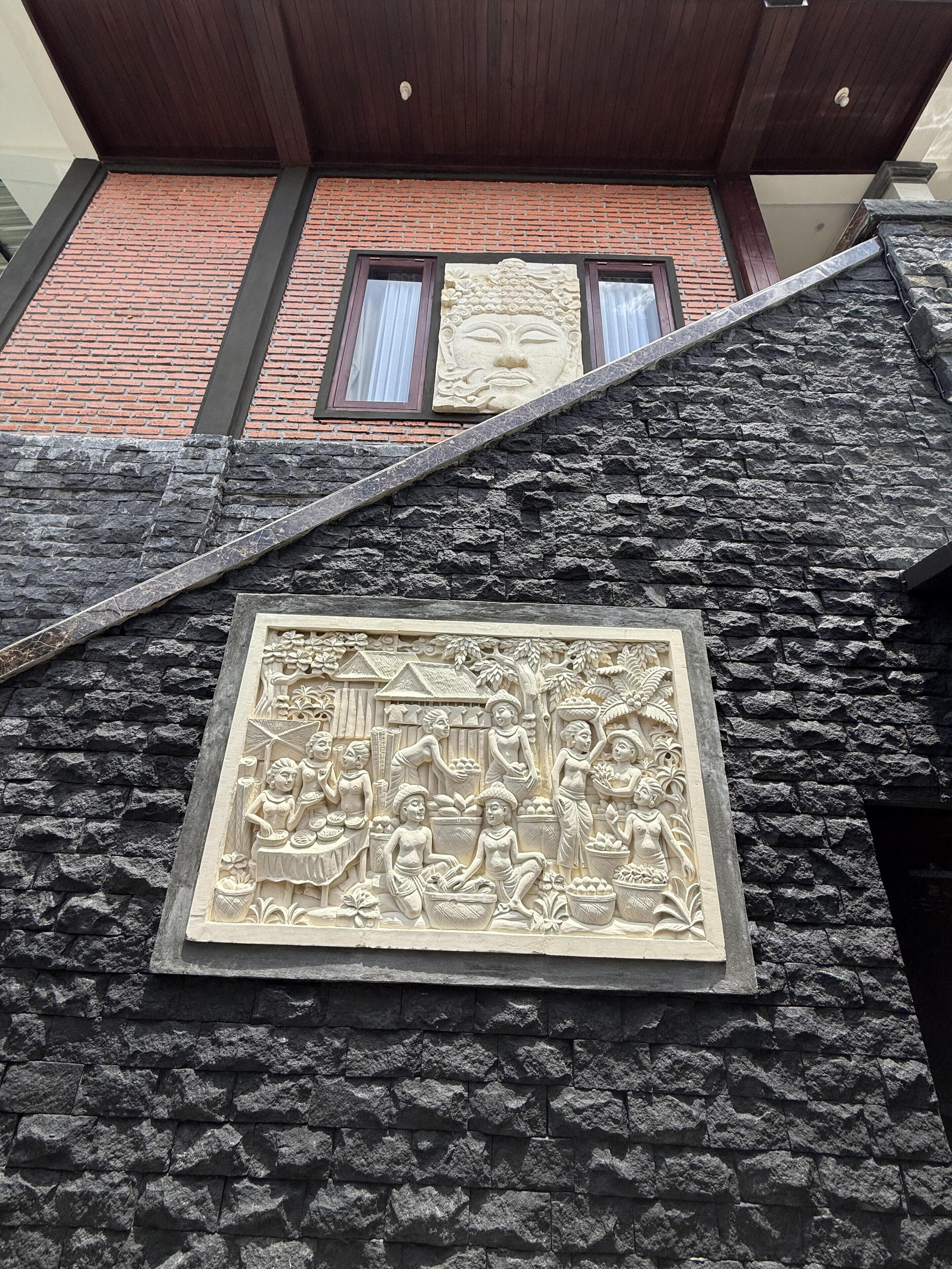 Una pared de piedra con un relieve que representa a un grupo de personas realizando diferentes actividades.