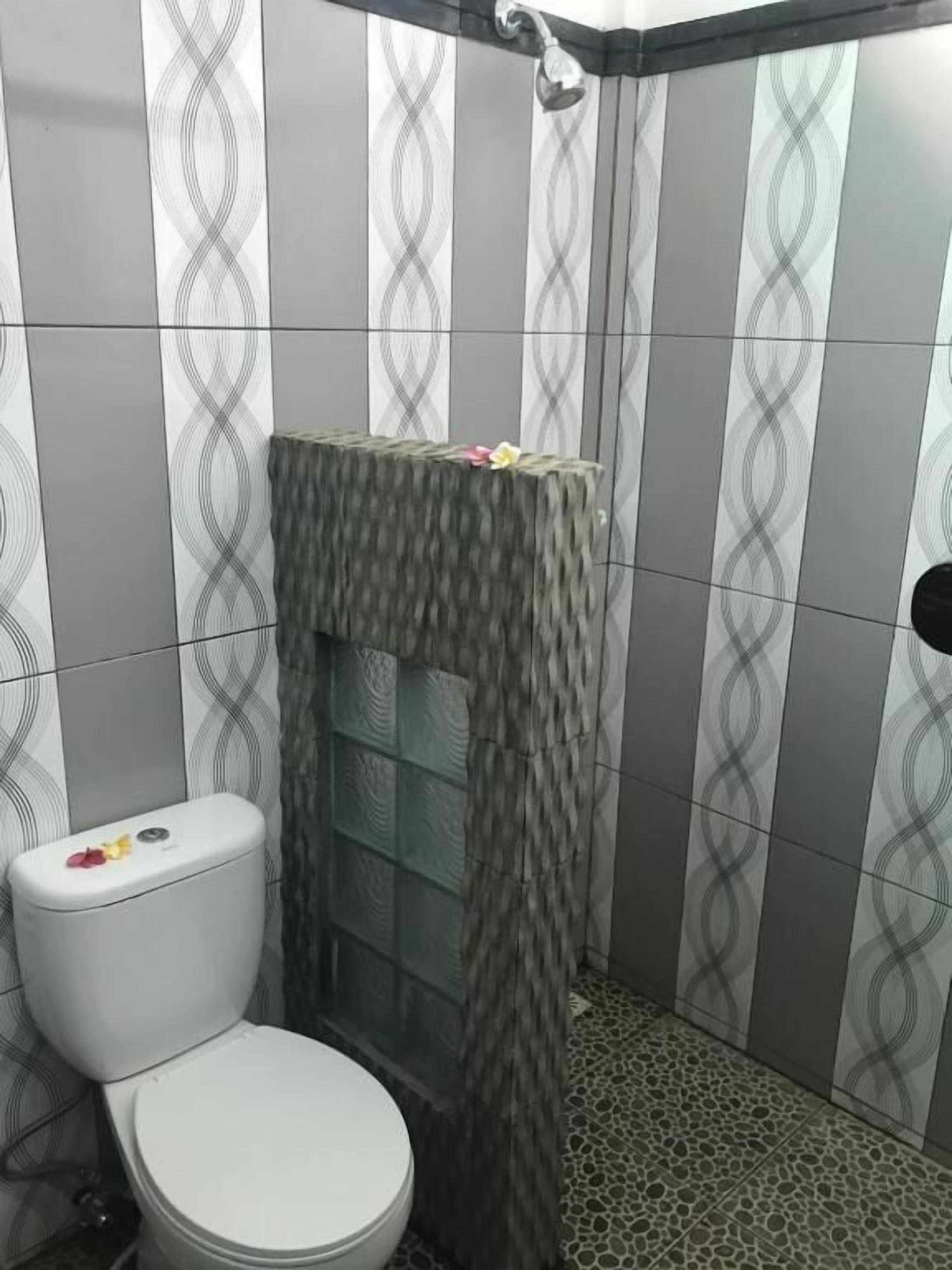 A bathroom with a toilet, a shower with a textured wall, and patterned tiles on the walls and floor.