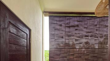 Un pasillo estrecho con una puerta de madera oscura a la izquierda, una ventana con persianas horizontales y un pequeño mostrador a la derecha.