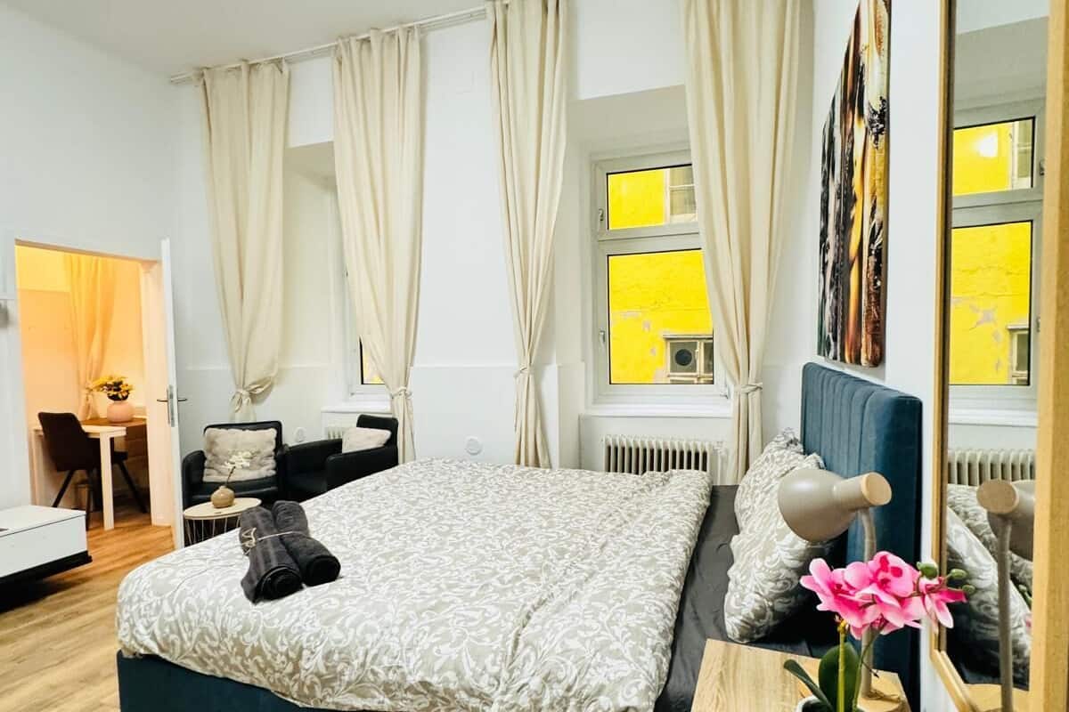 Een moderne slaapkamer met een groot bed, een nachtkastje met lamp, een spiegel en uitzicht op buiten.