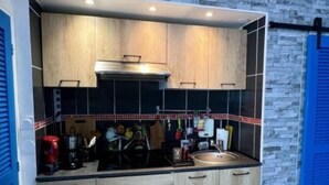 A compact kitchen with wooden cabinets, a built-in oven, and a black and white checkered floor.