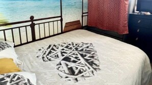 A bedroom with a bed, a view of the ocean, and a tropical-themed mural.
