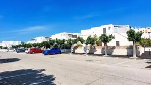 A parking lot with several cars and white buildings in the background.