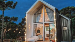 A modern house with a large glass window, a wooden deck, and string lights.