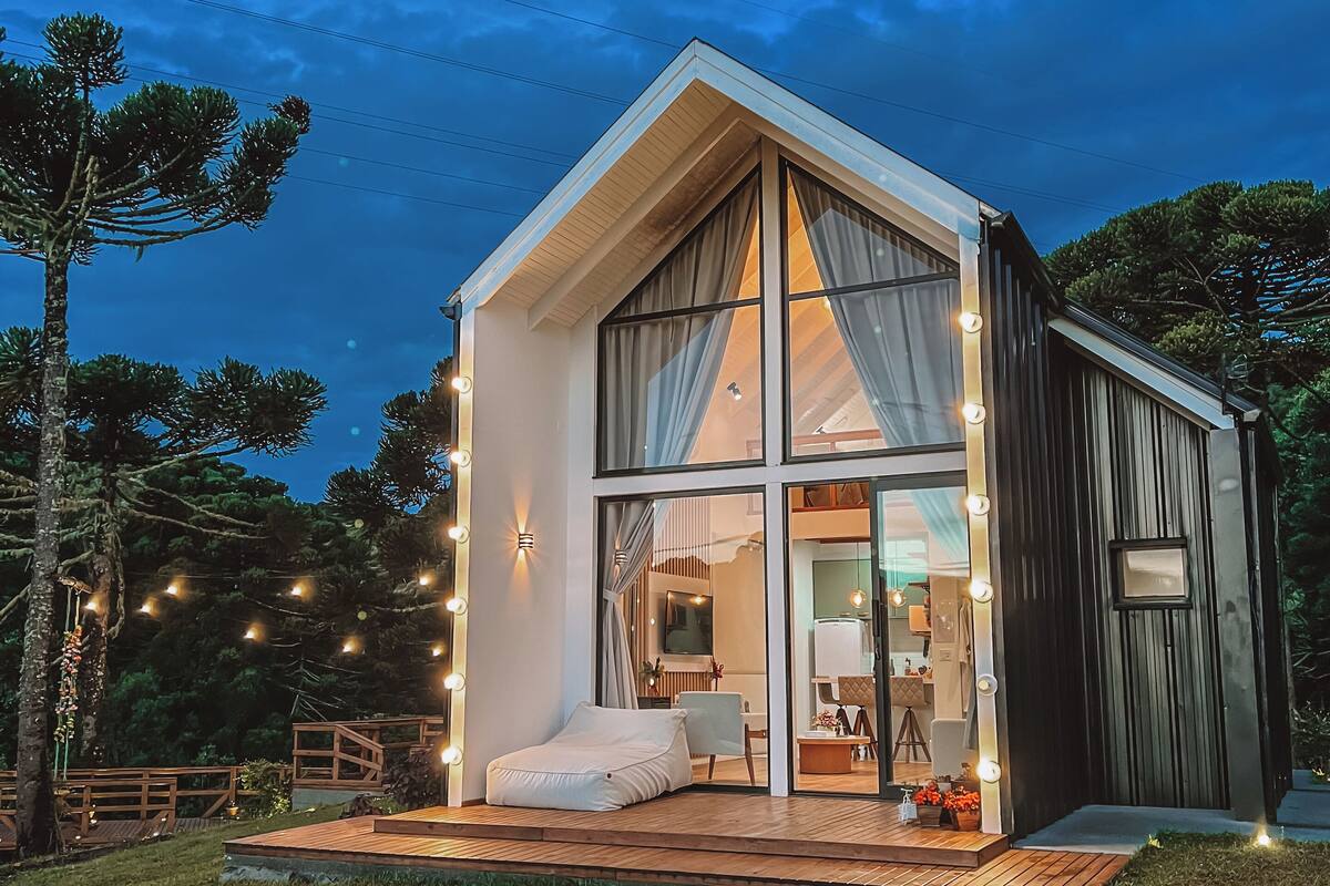 A modern house with a large glass window, a wooden deck, and string lights.