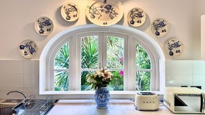 A kitchen with a white countertop, a dish rack, a toaster, and a window with a view of greenery. - Palazzo dei Fiori since 1883 (Balzan)