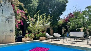 A swimming pool with a pink float, surrounded by white lounge chairs and potted plants. - Palazzo dei Fiori since 1883 (Balzan)