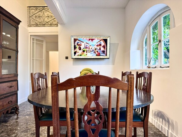 A dining area with a round table, six chairs, and a decorative wall piece.