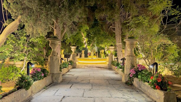 A stone pathway leading through a garden with a fountain at the end. - Palazzo dei Fiori since 1883 (Balzan)