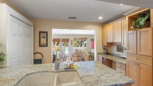 A kitchen with granite countertops, wooden cabinets, and a view to an outdoor patio area.
