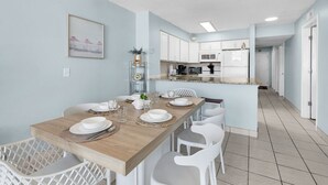 Una cocina moderna con armarios blancos, una mesa de comedor de madera y sillas blancas.