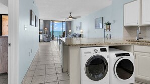 A modern kitchen with built-in appliances, a dining area with a view, and a laundry room. - Palms Resort 501: 3BR Oceanfront Condo (Myrtle Beach)