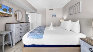 A bedroom with a bed, a dresser, a mirror, and a television on the wall. - Palms Resort 501: 3BR Oceanfront Condo (Myrtle Beach)