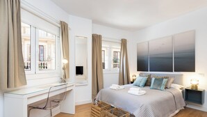 Un dormitorio moderno con cama, mesitas de noche, un escritorio y cestos de mimbre.