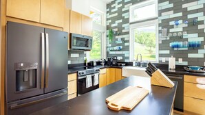 A modern kitchen with stainless steel appliances, wooden cabinets, and a black countertop. - Happy Heart House: Elegant 2-bedroom house with stunning views close to the park (Three Rivers)