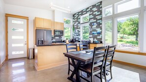A modern kitchen with a central island, wooden cabinets, and large windows offering a view of greenery. - Happy Heart House: Elegant 2-bedroom house with stunning views close to the park (Three Rivers)