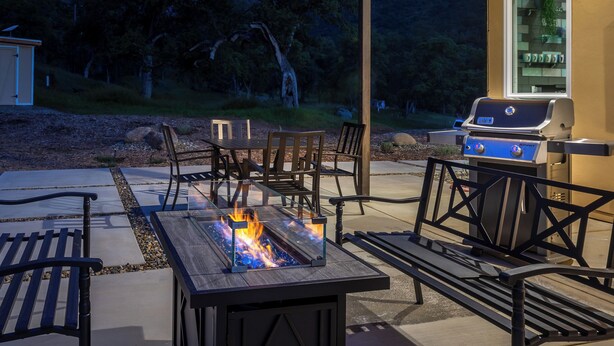 An outdoor patio with a fire feature, seating, and a barbecue grill. - Happy Heart House: Elegant 2-bedroom house with stunning views close to the park (Three Rivers)