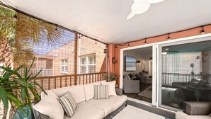 Een balkon met een bank, een bijzettafeltje en een bloempot.