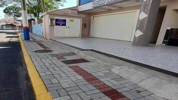 Una acera con bordillo amarillo, un edificio con persiana cerrada y un cartel que dice 'Edificio'.