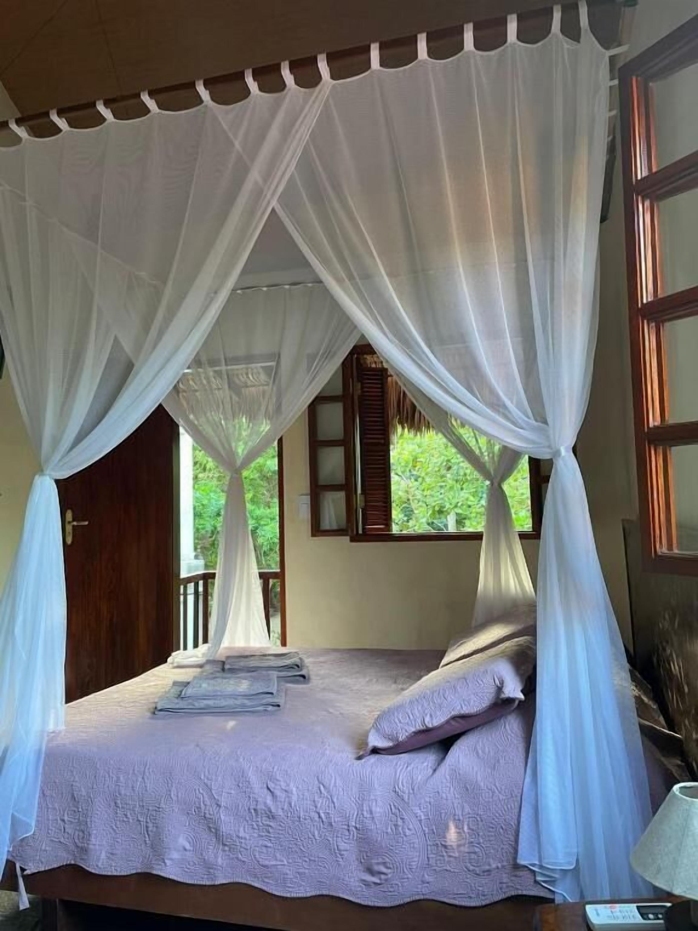 Una cama con dosel, una puerta de madera y una ventana con contraventanas.