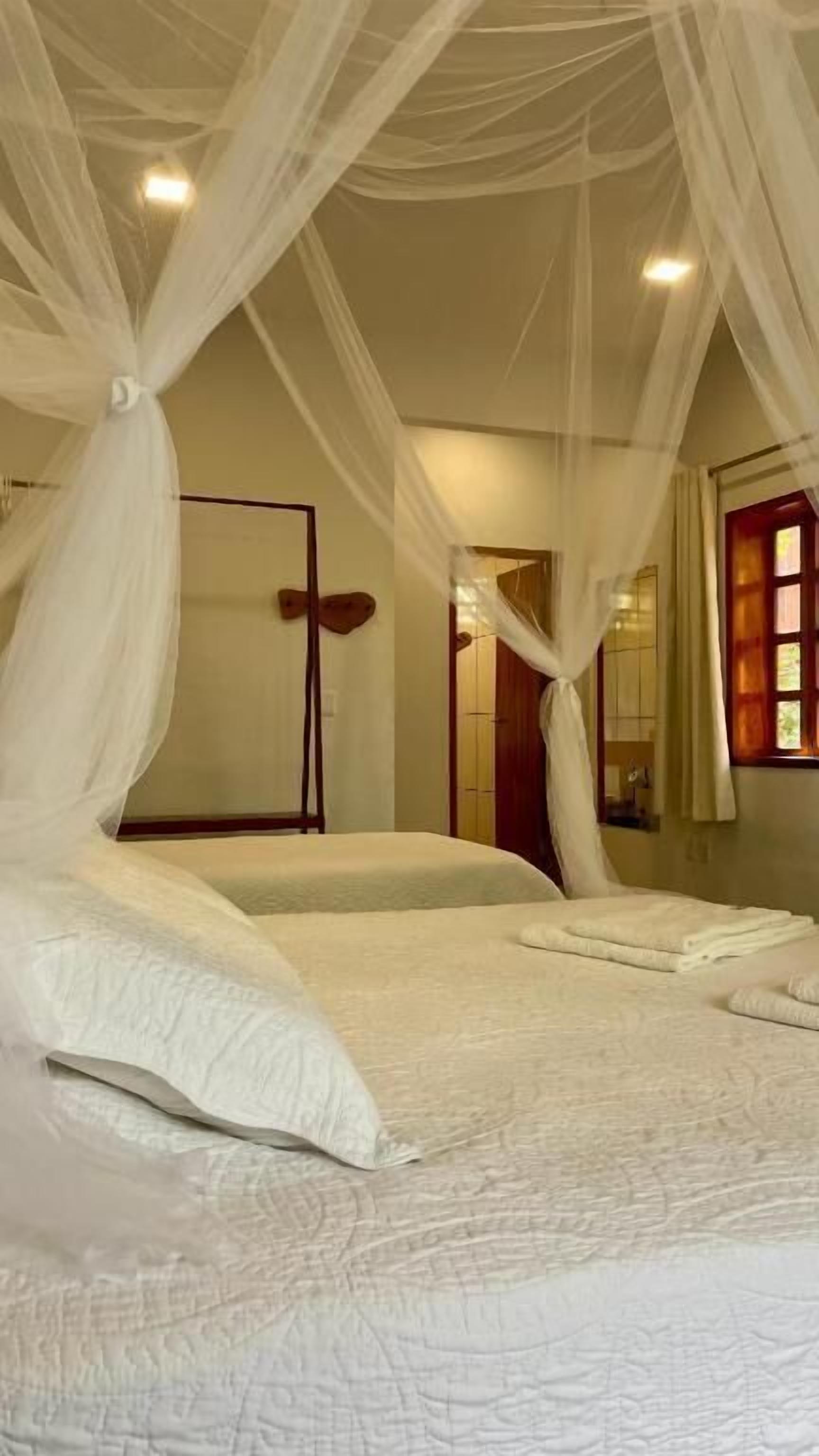 Un dormitorio con una cama grande, ropa de cama blanca y un dosel.