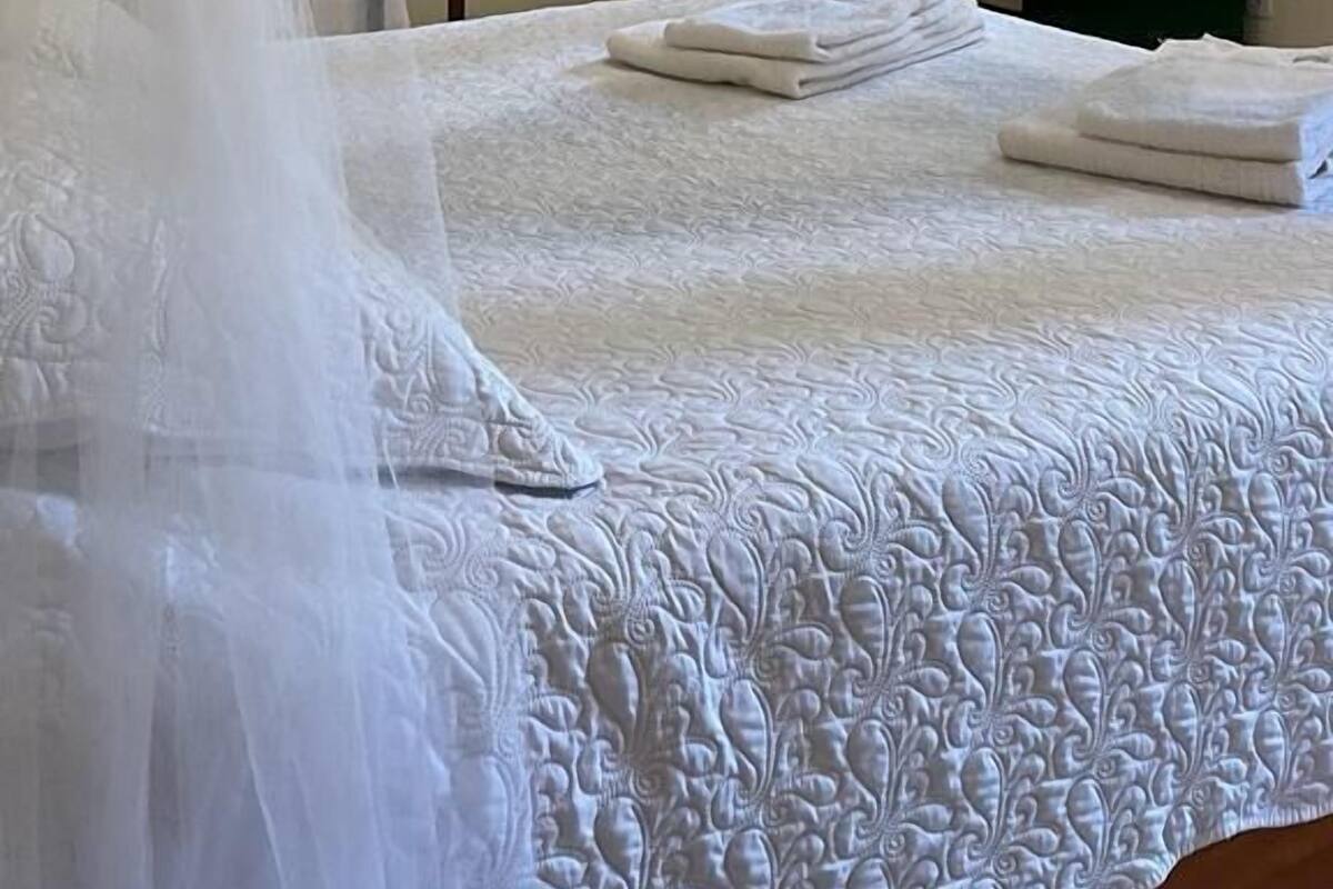 A bed with a white canopy and a neatly made bedspread.