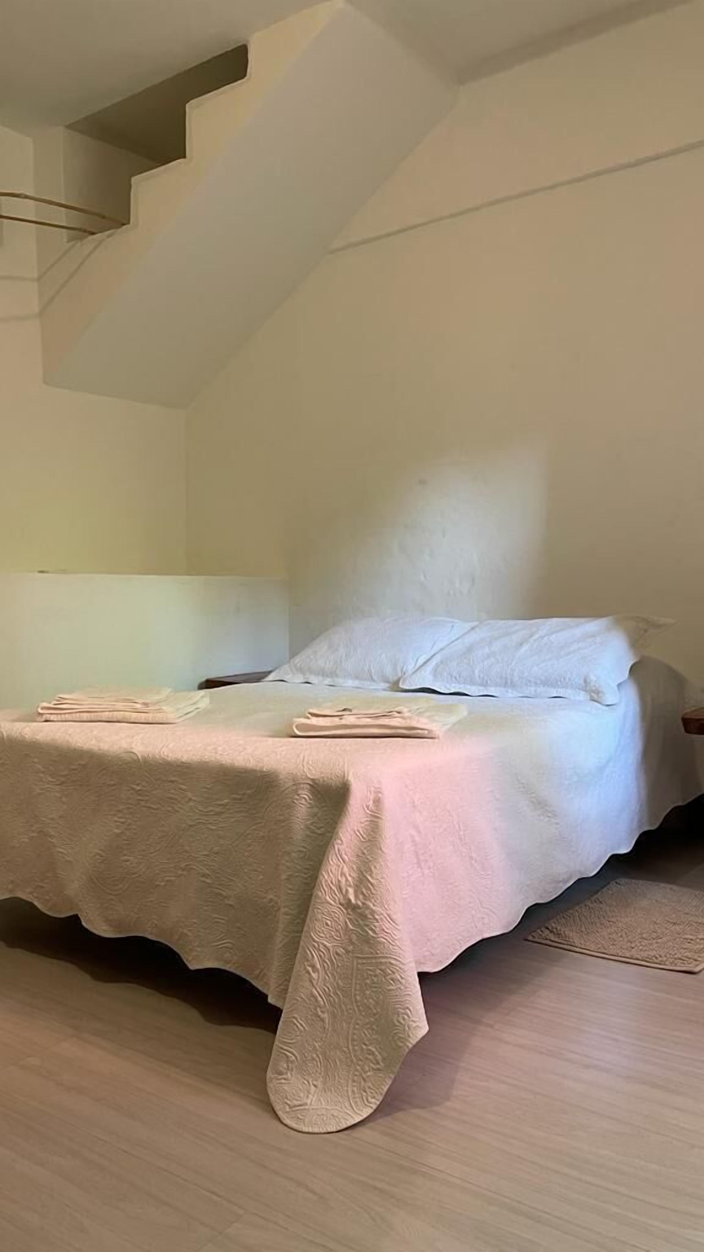 A bedroom with a bed, a headboard, and a staircase.
