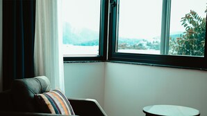 Une pièce avec une fenêtre donnant sur un beau paysage, une chaise et une petite table.