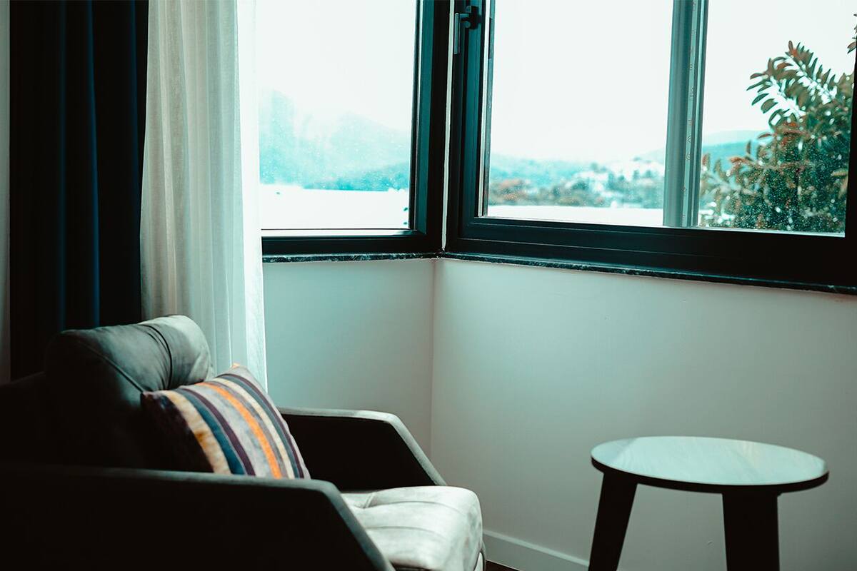 A room with a view through a window, a chair, and a small table.