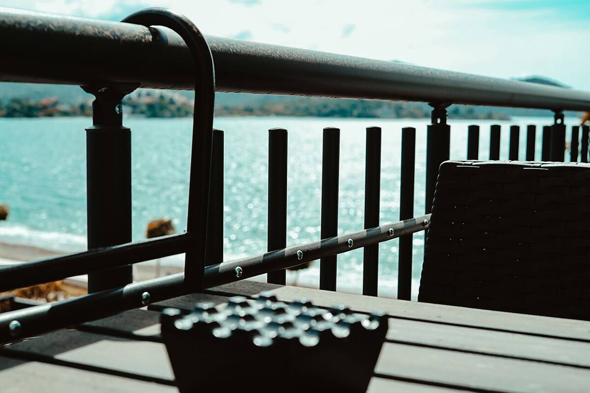 A wooden deck with a metal railing overlooking a body of water.