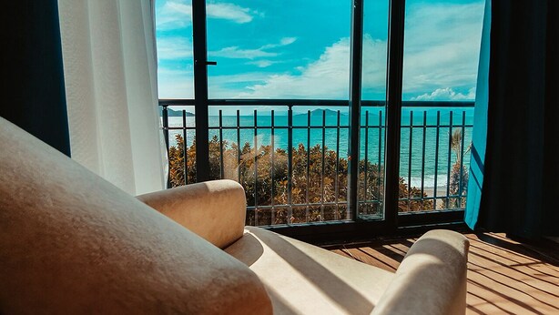 Un balcon avec vue sur l’océan et une chaise.