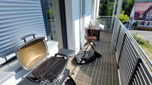 A covered outdoor area with a grill, seating, and a view of the surrounding neighborhood.
