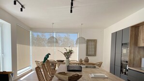 A modern kitchen with a wooden island, wicker chairs, and a large window.