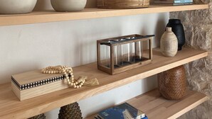 A wooden shelf with various decorative items including pottery, a woven basket, and books.