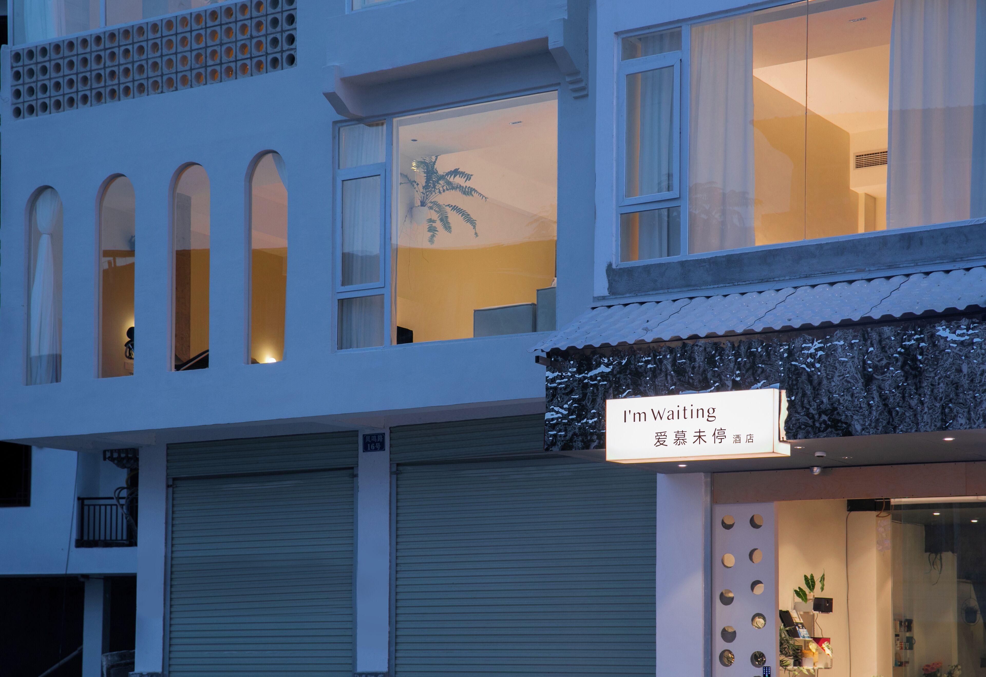 Un hotel con un cartello che recita 'I'm Waiting' e una palma visibile dalla finestra.