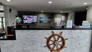 Ein Empfangsschalter mit nautischem Steuerrad, ein Monitor mit Sicherheitsaufnahmen und ein Willkommensschild für das Lakeview Inn.